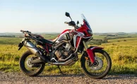 Una motocicleta de aventura Honda Africa Twin estacionada en un camino rural despejado bajo el cielo de Uruguay.