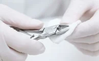Limpieza técnica de un alicate de cutículas de acero quirúrgico con un algodón empapado en alcohol isopropílico.