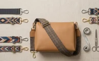 Varios bolsos con herrajes de metal y carteras con correa utilitaria de cinta tejida satinada de diferentes tonos.
