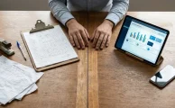 Escritorio con una planilla de registro manual de horas extra en papel a la izquierda y una tablet con el control digital de asistencia a la derecha